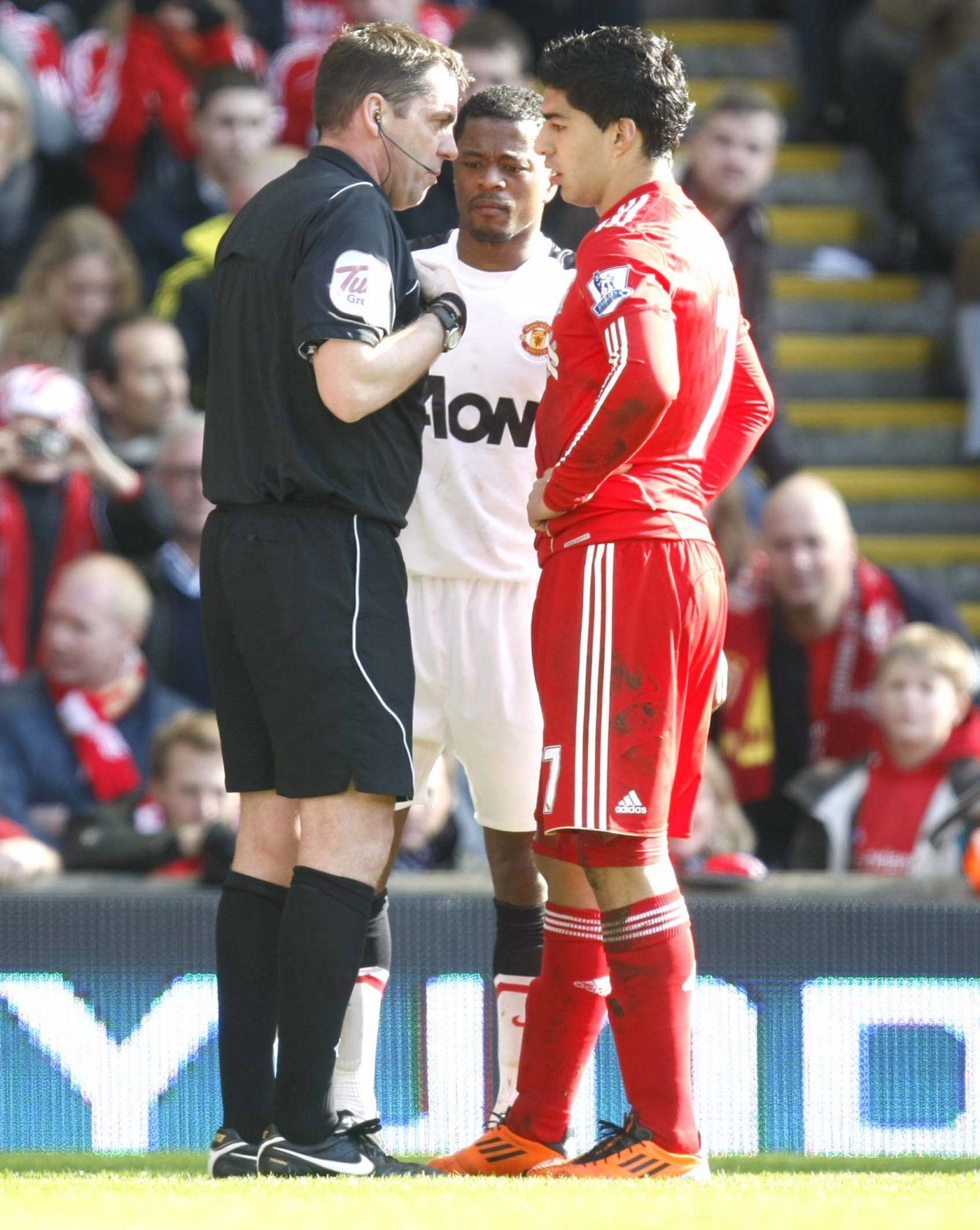 The referee talks to Luis Suarez and Patrice Evra