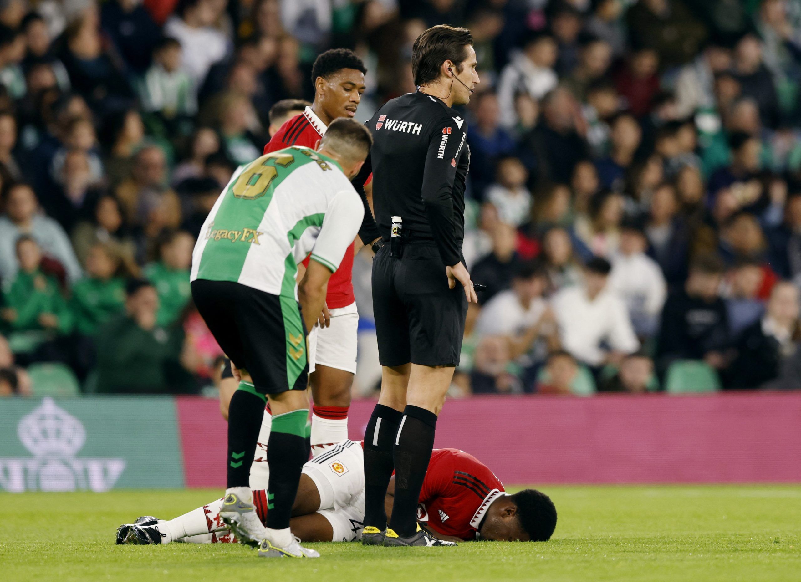 Soccer Football - Friendly - Real Betis v Manchester United - Estadio Benito Villamarin, Seville, Spain - December 10, 2022  Manchester United's Teden Mengi goes down after sustaining an injury as Anthony Martial, referee Jose Luis Munuera Montero and Real Betis' Victor Ruiz look on  REUTERS/Marcelo Del Pozo