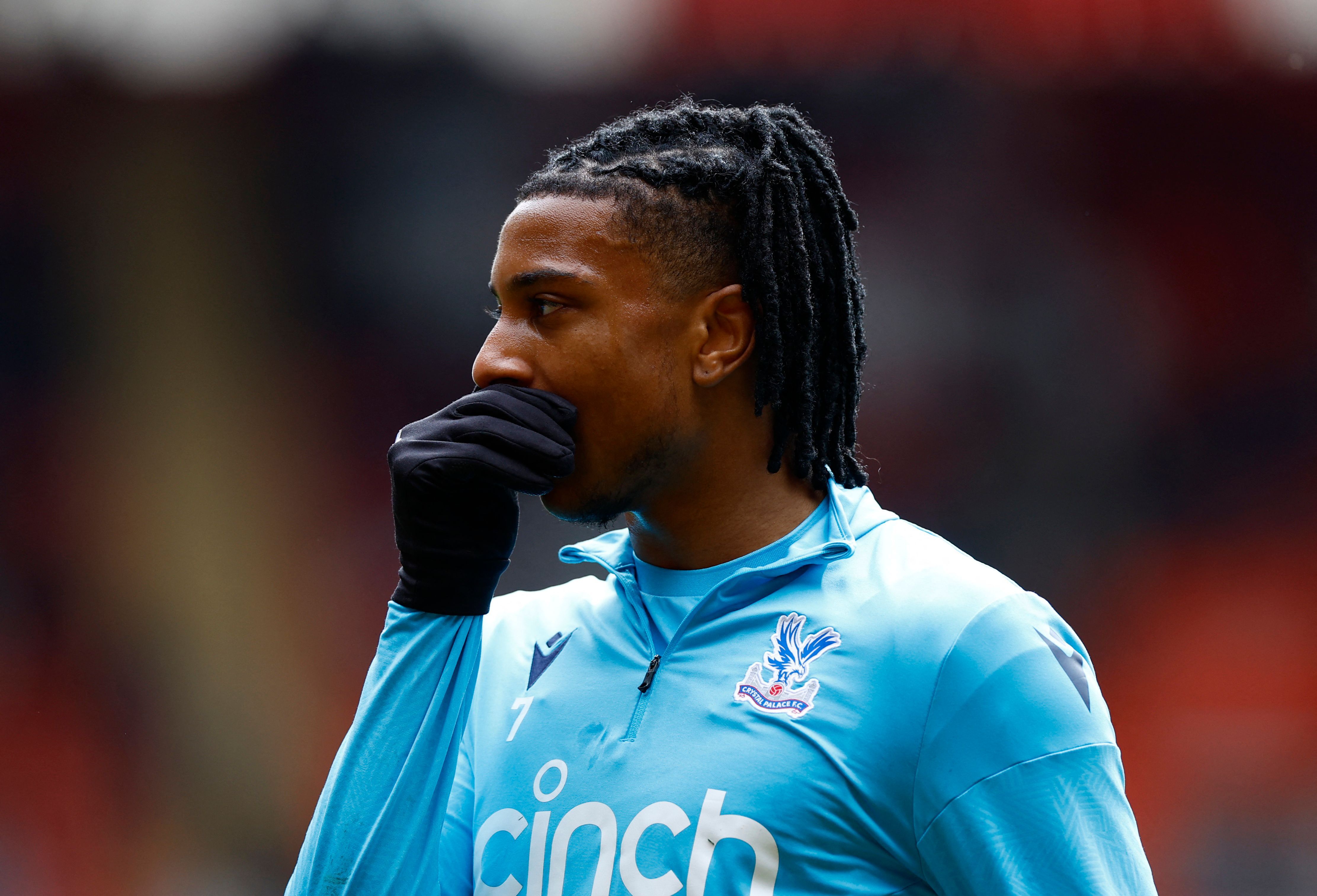  A photo of Michael Olise, a Crystal Palace player, wearing a blue and white jacket with the logo of his team on the chest.