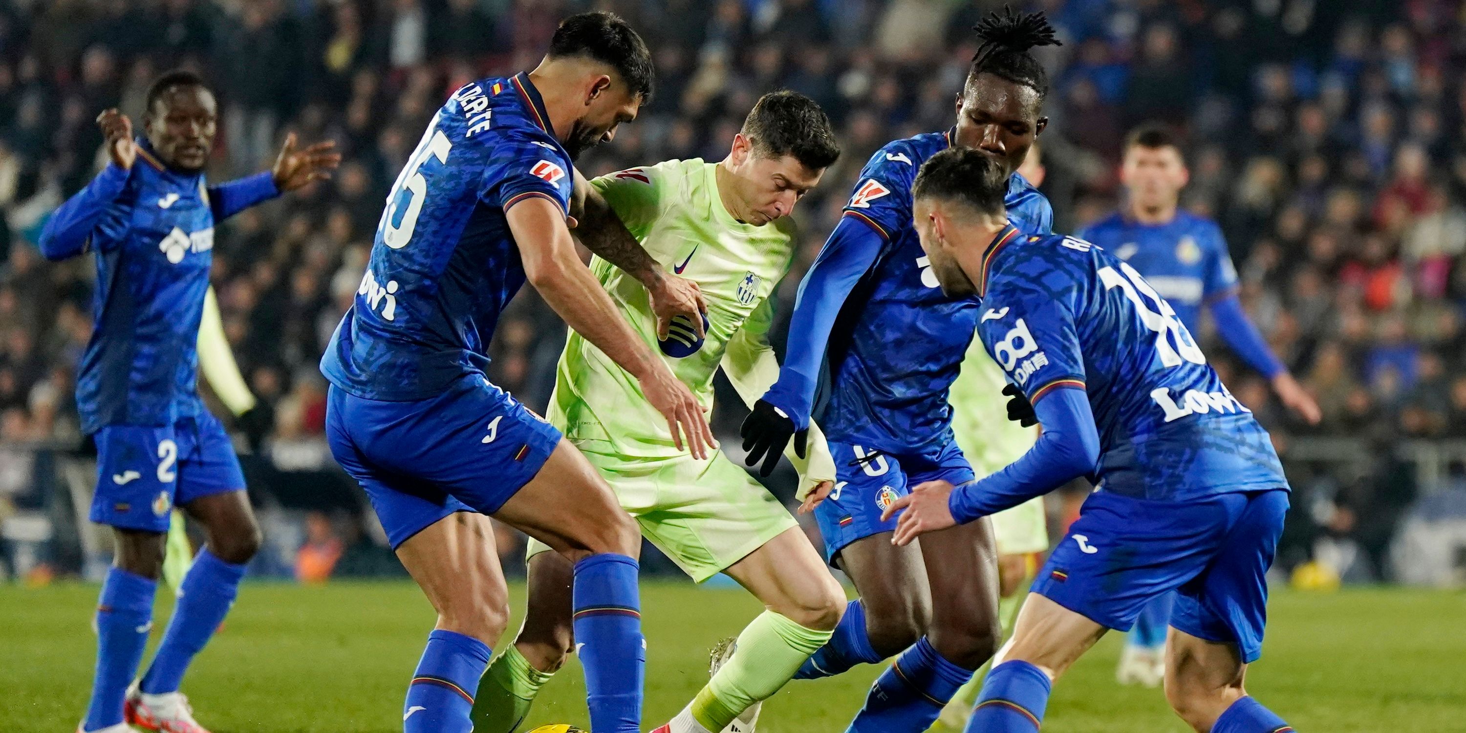 Christantus Uche del Getafe en acción con Robert Lewandowski del FC Barcelona