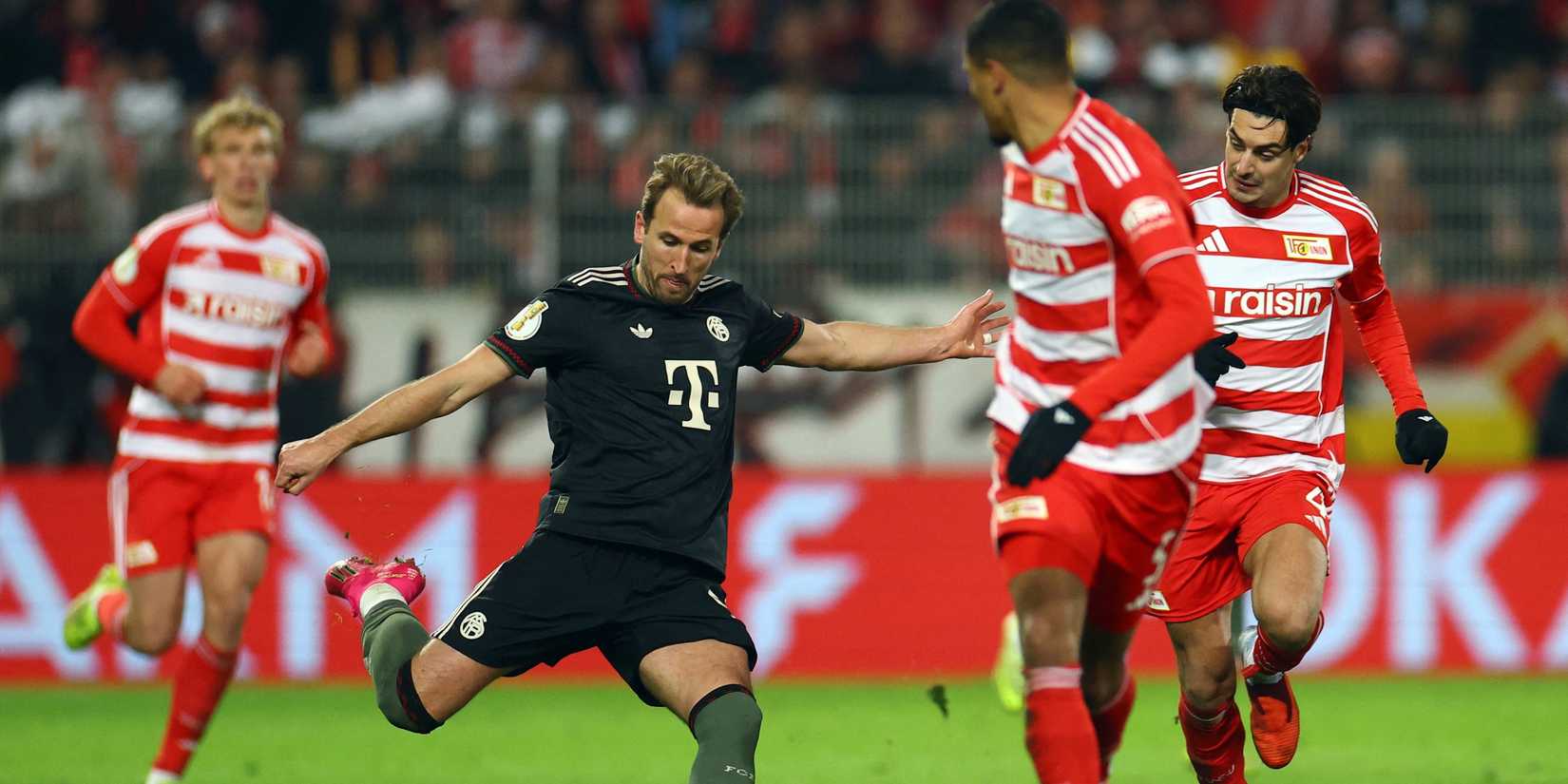 Bayern Munich's Harry Kane in action with 1. FC Union Berlin's Danilho Doekhi and Diogo Leite