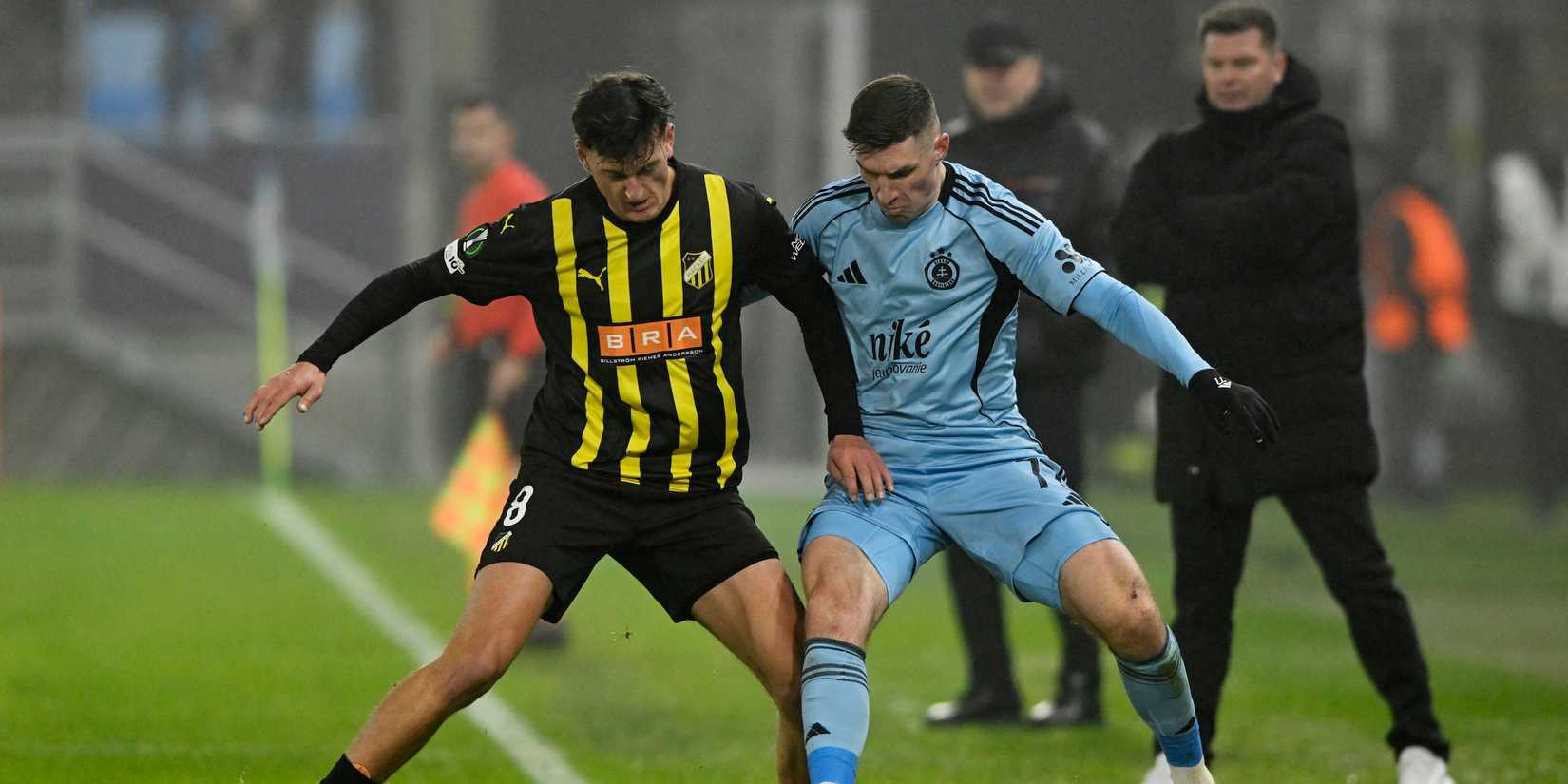 Silas Andersen of BK Hacken plays against Danylo Ignatenko of Slovan Bratislava as BK Hacken coach Jens Gustafsson looks on