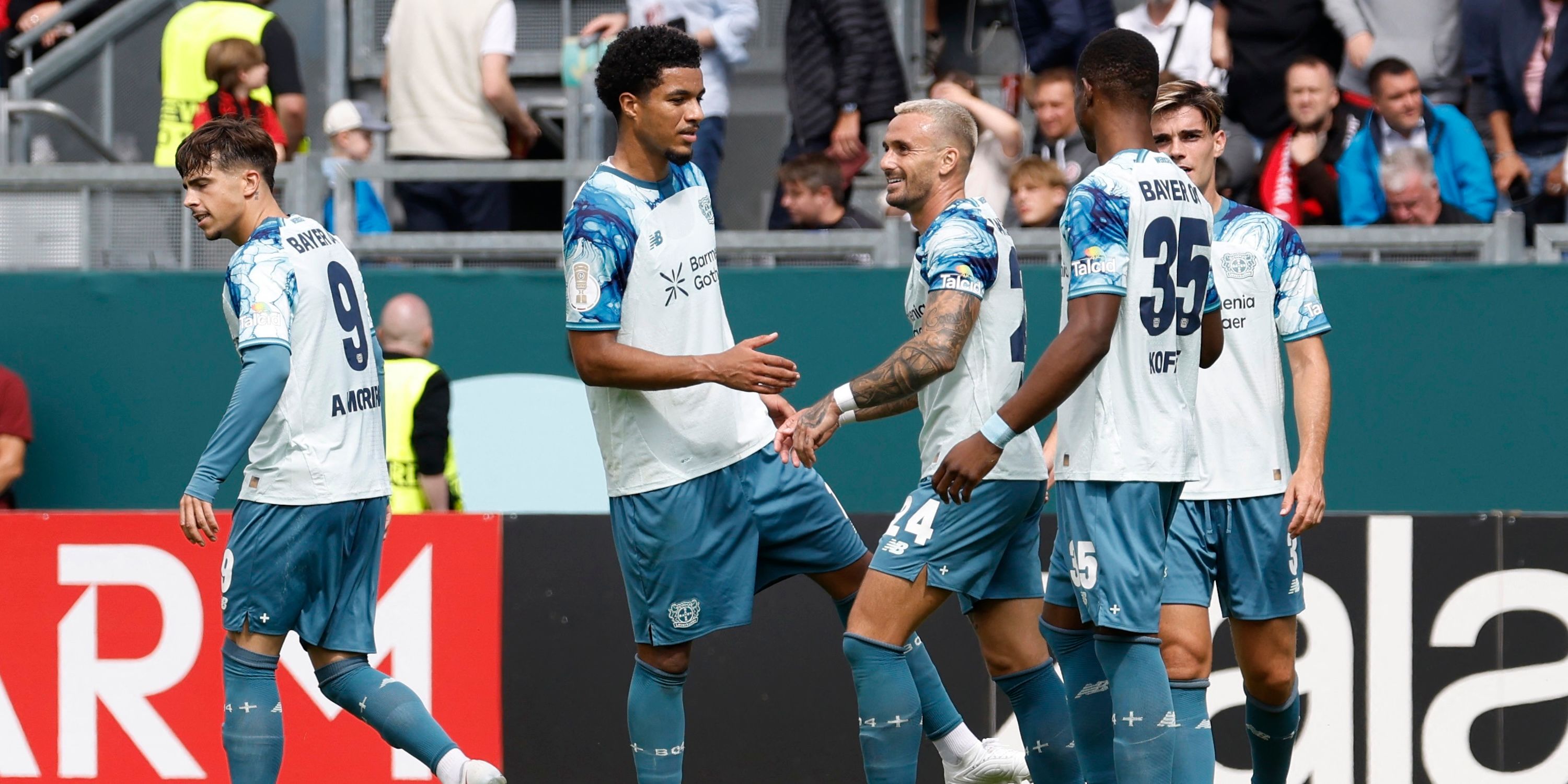 Bayer Leverkusen's Christian Kofane celebrates scoring their fourth goal with teammates